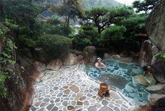 Japans bad in de buitenlucht, eromheen staan naaldbomen